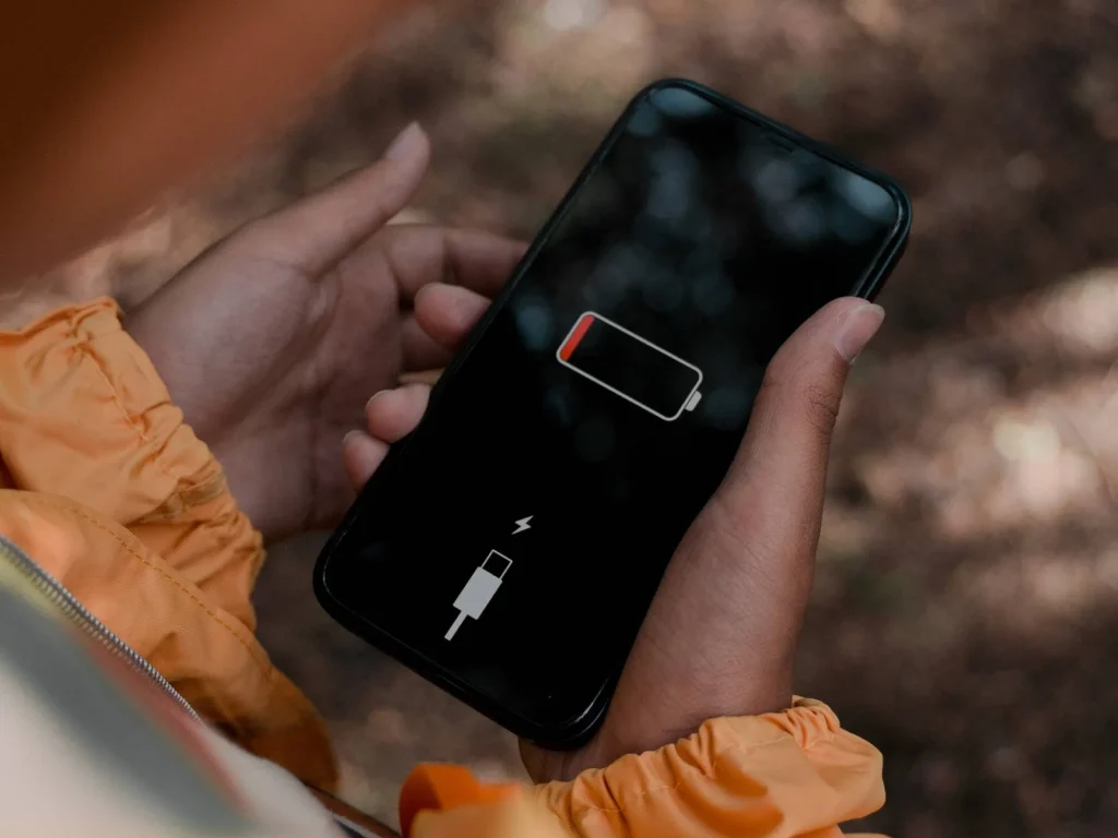 Person holding a smartphone showing a critically low battery symbol, illustrating battery drain issues on Android