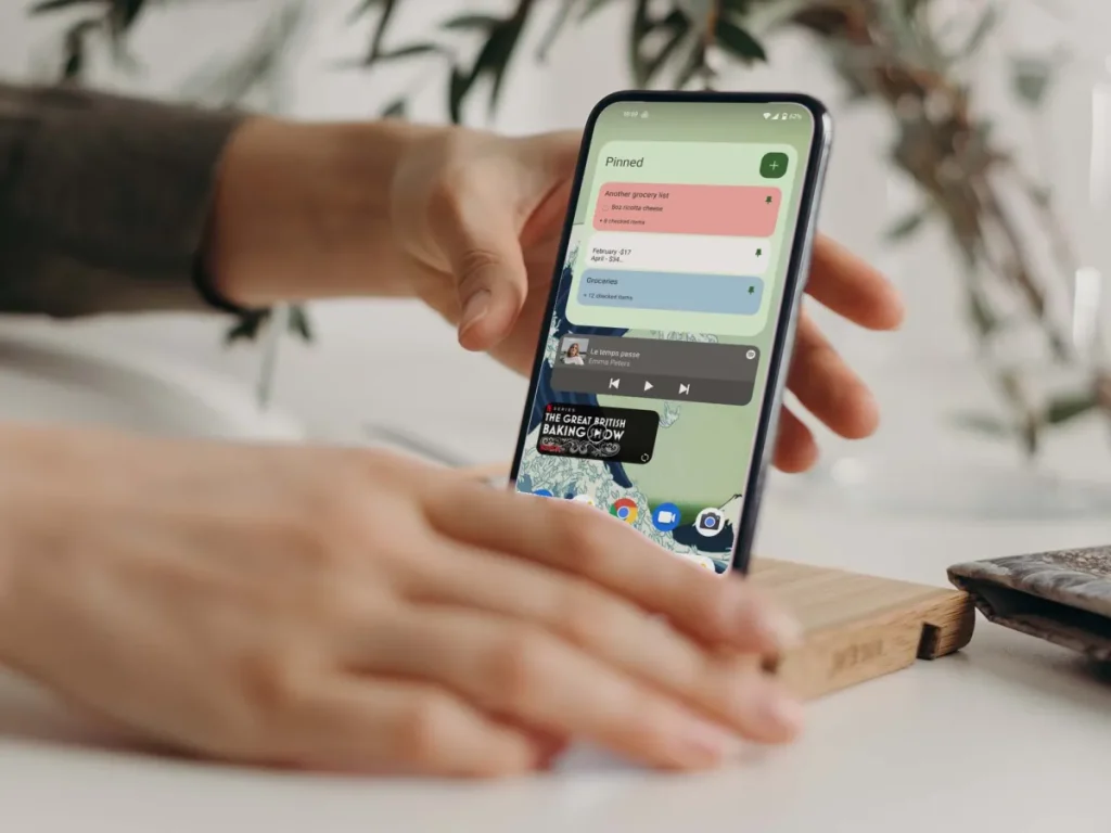 Hands placing an Android smartphone on a stand while the home screen and widgets are visible